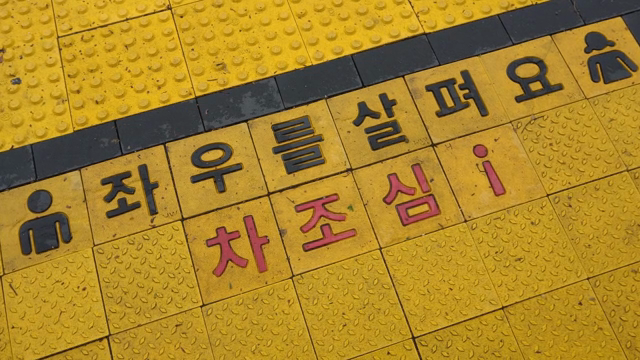 Yellow tactile paving with warning text