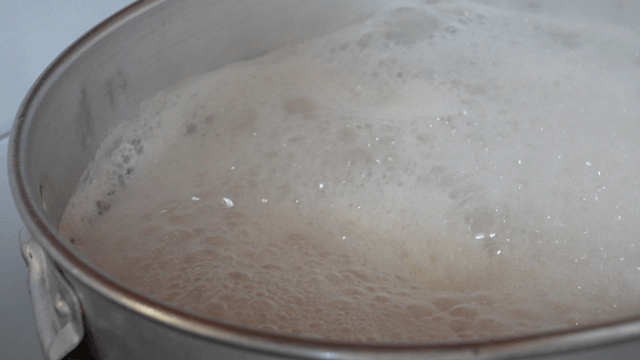 Foamy bone broth cooking in large pot