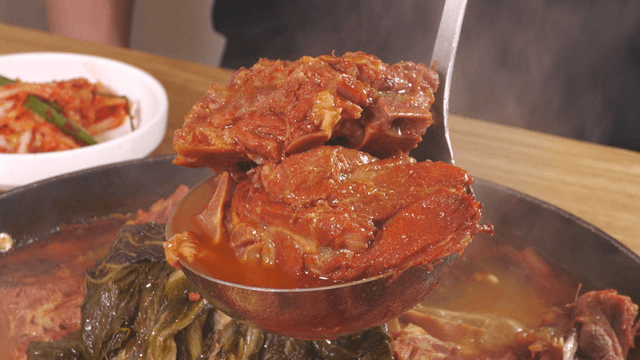 Ladle filled with generous pork back-bone meat from outer leaves stew
