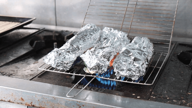 Foil-wrapped food grilling on a stove