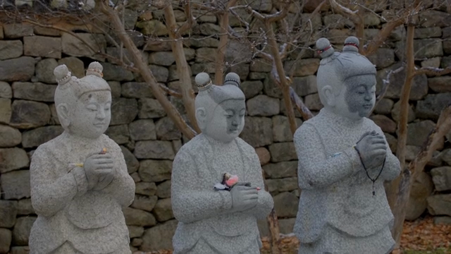 Three stone statues in a peaceful garden