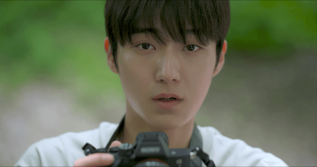 Young man holding a camera in a forest