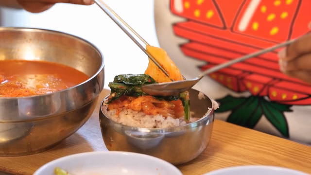 Young summer radish kimchi being placed on rice in a bowl