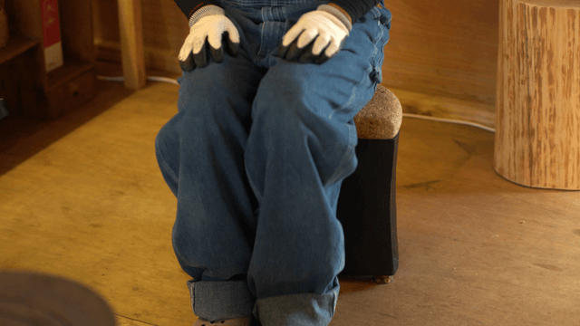 Person sitting on a small cork wooden chair