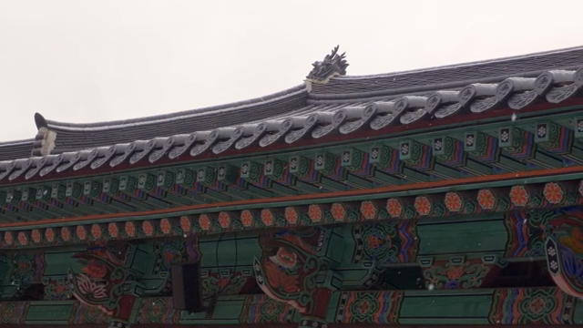 Traditional Korean temple architecture with snow falling