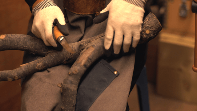 Person carving wood with a knife indoors