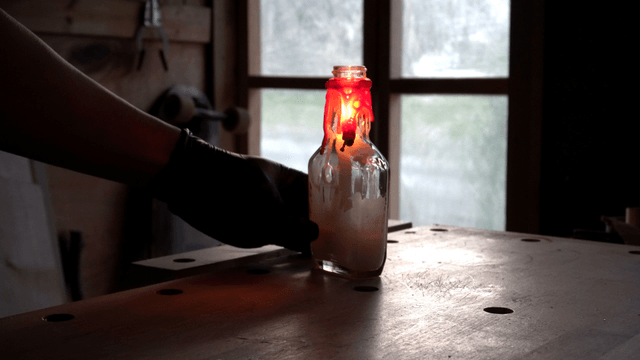 Candle burning in a glass bottle indoors