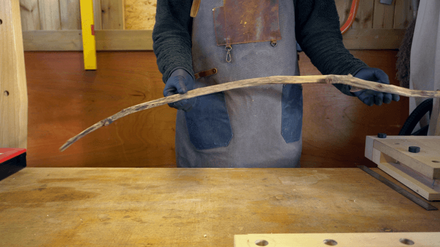 Person crafting with a wooden stick indoors