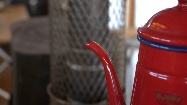 Spout of a red kettle releasing white steam