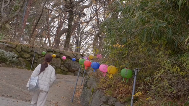 Woman walking down a street lined with colorful lanterns