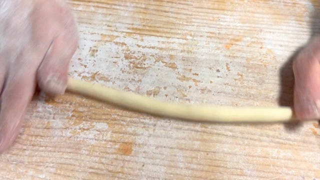 Hands shaping dough on a floured surface