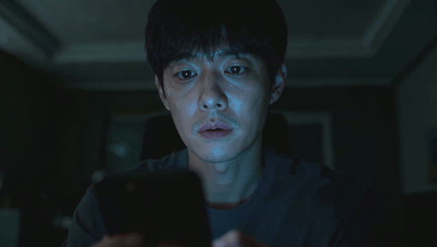 Man staring at phone screen in dark room