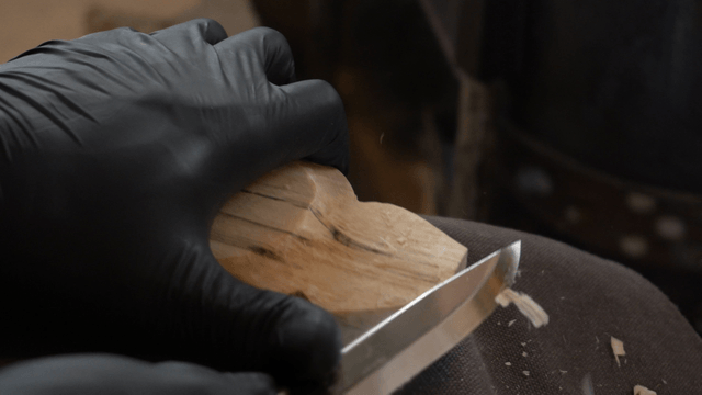 Hands carving wood delicately with a knife