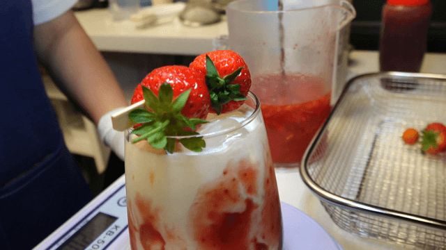 Strawberry latte topped with fresh strawberry skewer