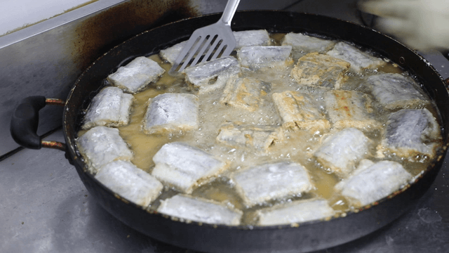 Fish being fried in a pan with oil
