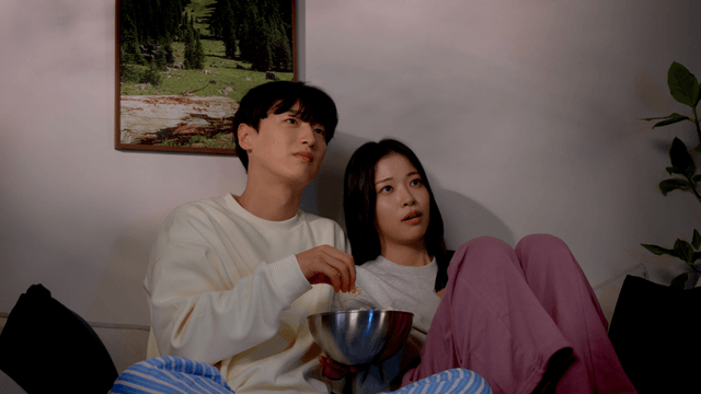 Couple watching TV together while eating popcorn on sofa