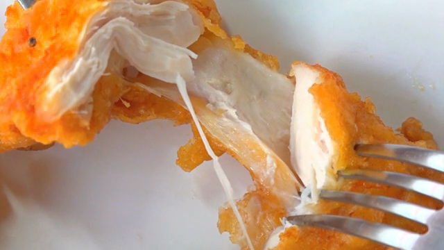 Fried chicken being pulled apart with forks