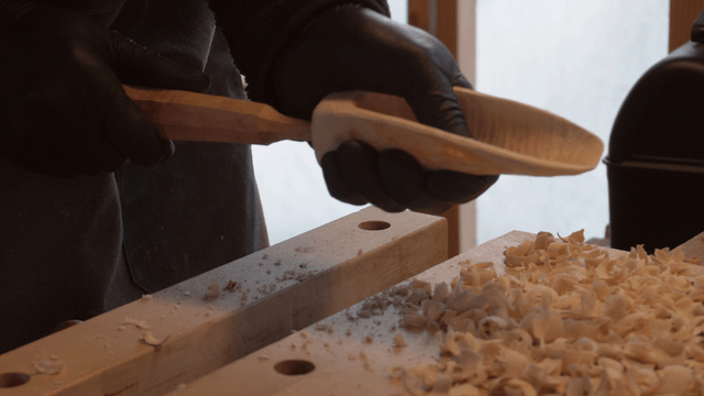 Woodcraft artisan attaching wooden scoop handle in workshop