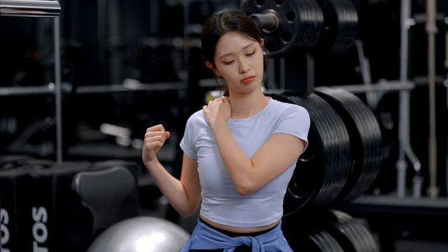 Young woman checking shoulder injury at gym