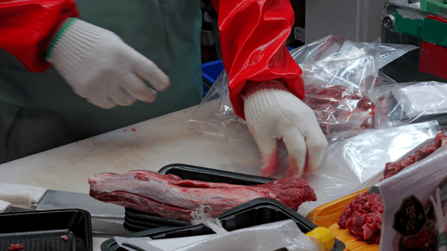 Butcher packing fresh meat in plastic bags