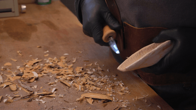 Wooden serving spoon head being carved with a knife