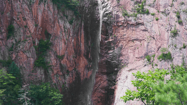 Thin waterfall falling from high cliff