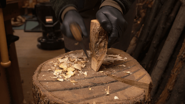 Woodcraft artisan carving wood with an axe in a cozy workshop