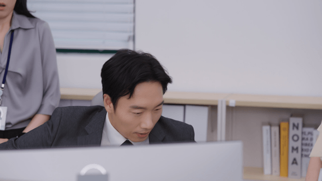 Office workers gathered around a desk, being scolded
