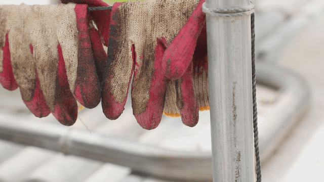 Dirty work gloves hanging on a metal pole
