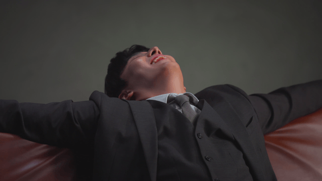 Cash raining down on a man sitting on a sofa