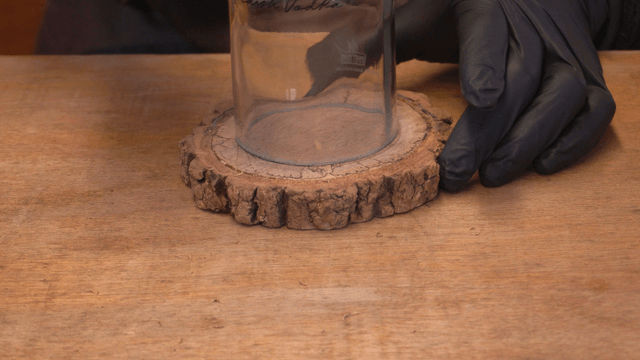 Artisan positioning a glass bottle spot on wooden piece