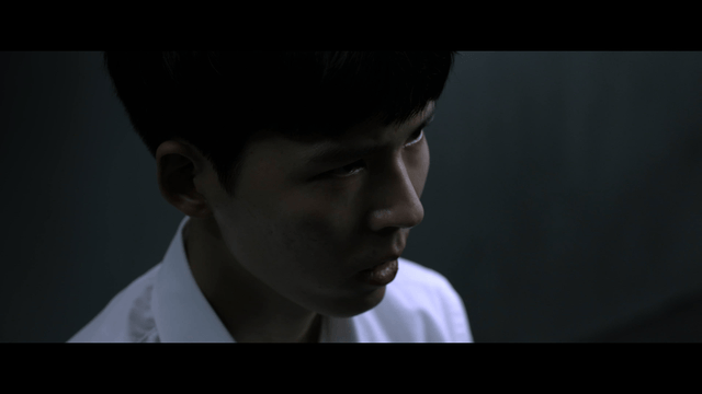 Young man speaking while standing in dark room