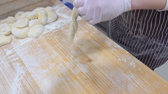 Hands shaping dough on a floured surface
