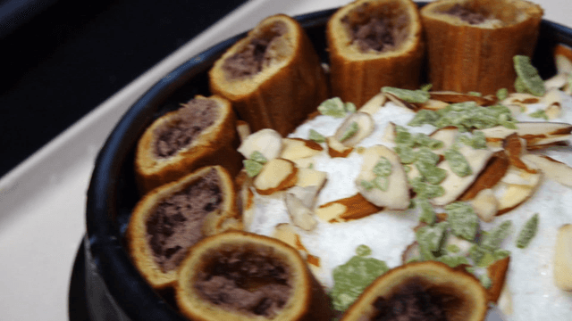 Shaved ice dessert in earthenware bowl with red bean bun and almonds