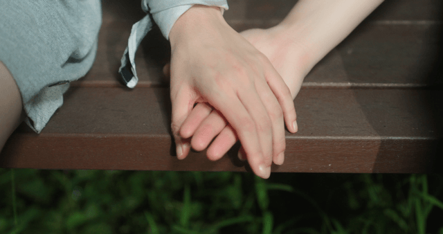 Two people holding hands on a bench