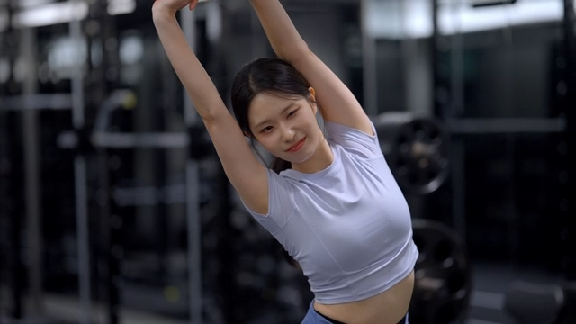 Side view of young woman stretching arms at gym