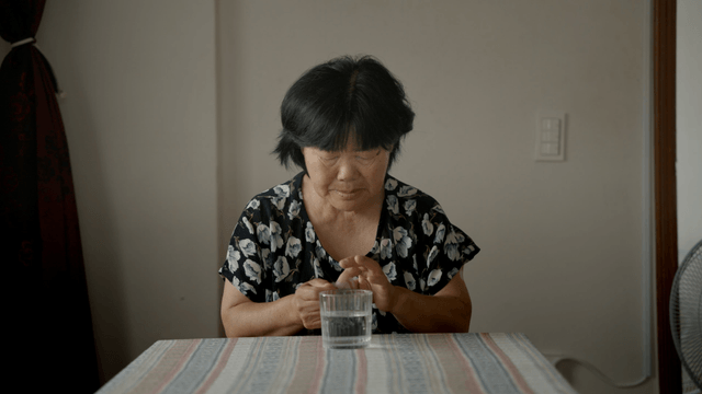 약 봉투 뜯는데 어려움을 겪는 노인 여성