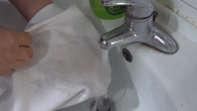 Hand washing a white cloth in a sink