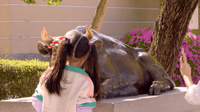 Child posing for photo in front of bull statue