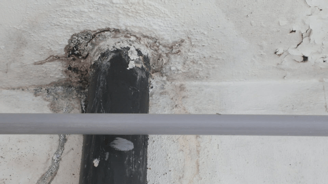 Close-up of a damaged wall with a pipe