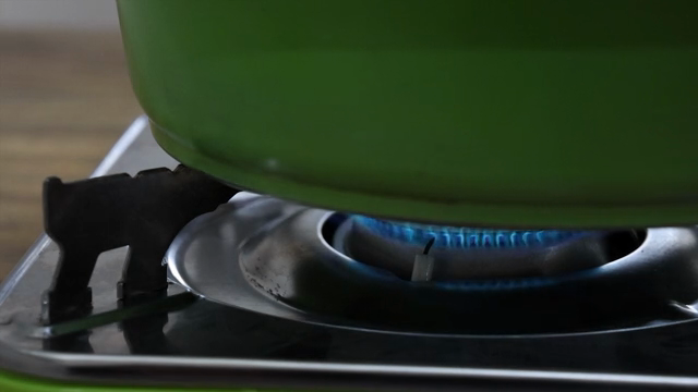 A green pot heating on a gas stove