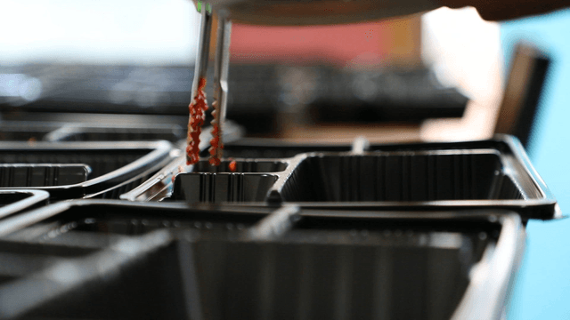 Kimchi being placed into food containers