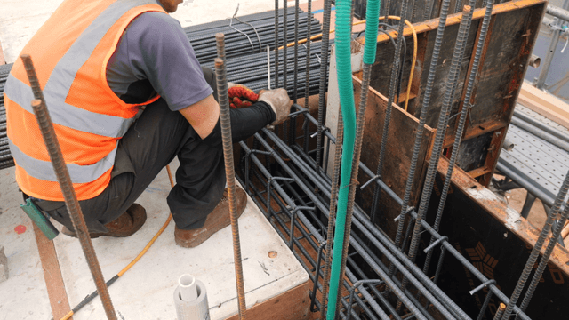 Construction worker securing rebar on site