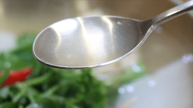 Spoon scooping clear broth of cod soup