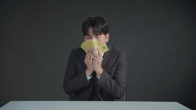 Man smelling money with a satisfied expression