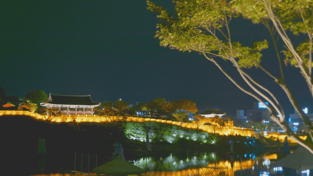 Lights over riverside illuminating traditional hanok pavilion and fortress