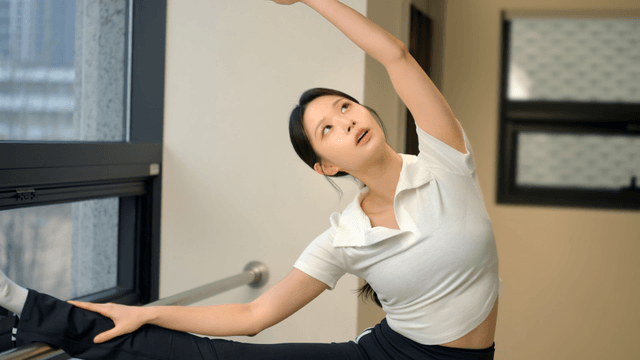 Young woman stretching by the window