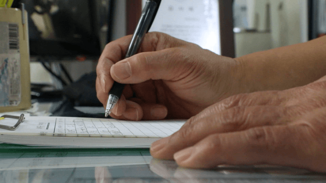 Person writing notes on a clipboard