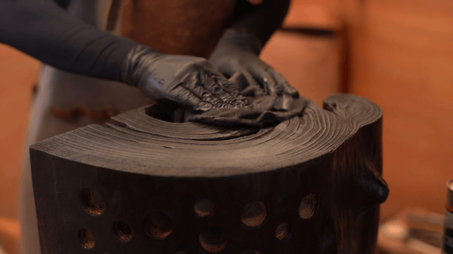 Artisan applying oil to wooden sculpture