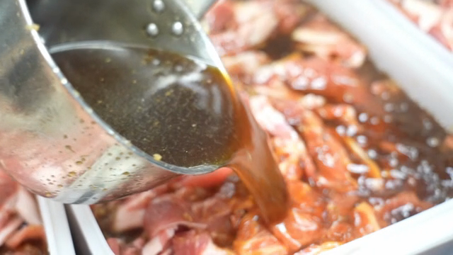 Marinating meat with sauce in a container